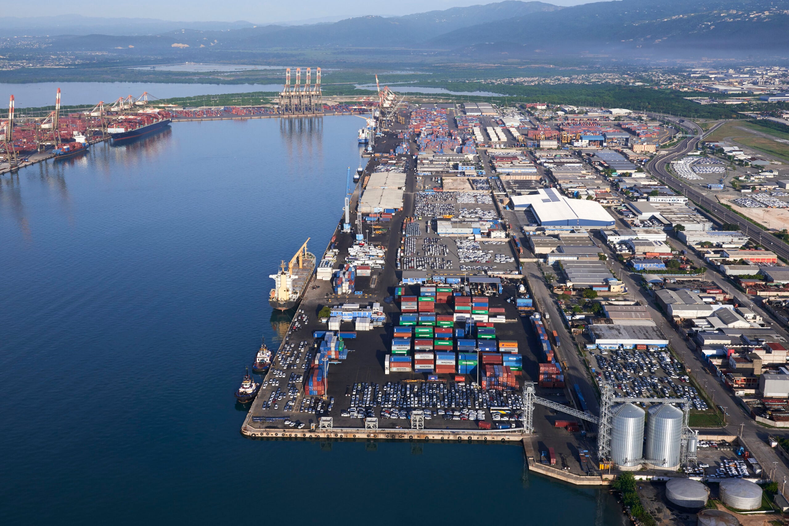 Aerial view of container terminals, warehouses and cargo ships around a harbor.